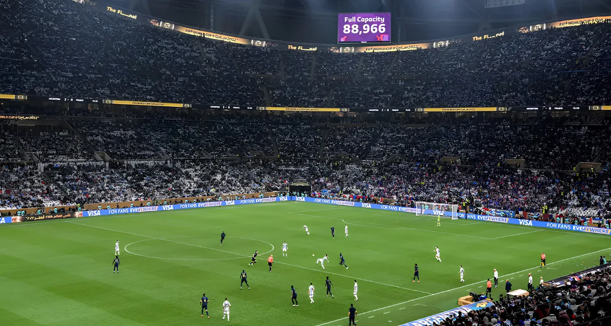 Packed stadium during the 2022 FIFA World Cup final, showing the soccer field and a jumbotron reading 88,966 full capacity.